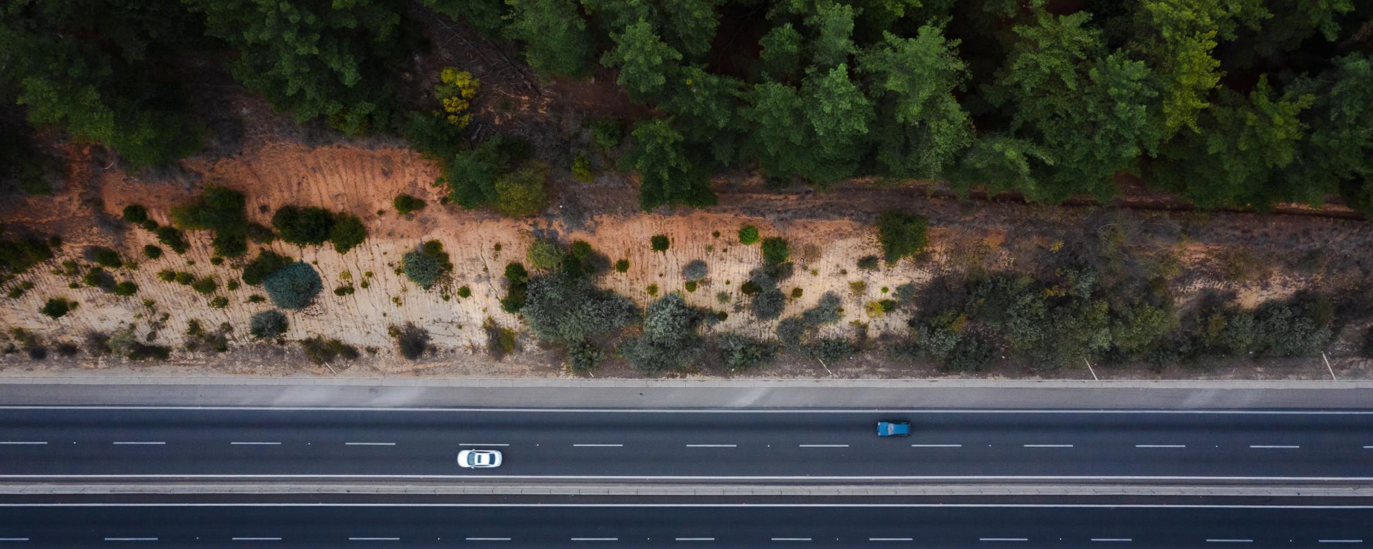 drone image of a car driving down a coastal road